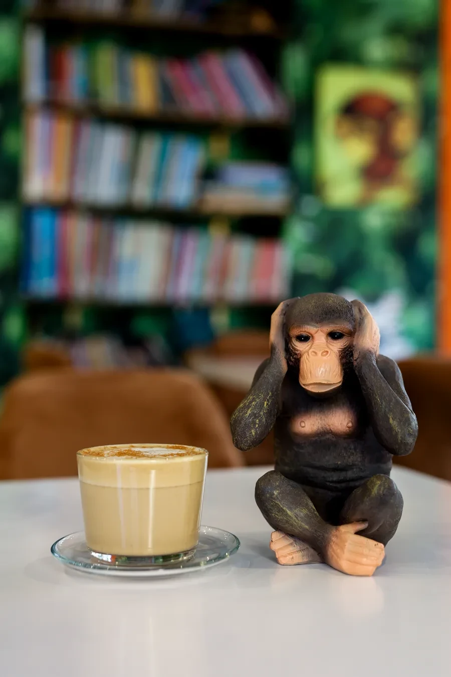 Kawa na stoliku w Zizi Cafe, obok figurka małpki, w tle półka z książkami