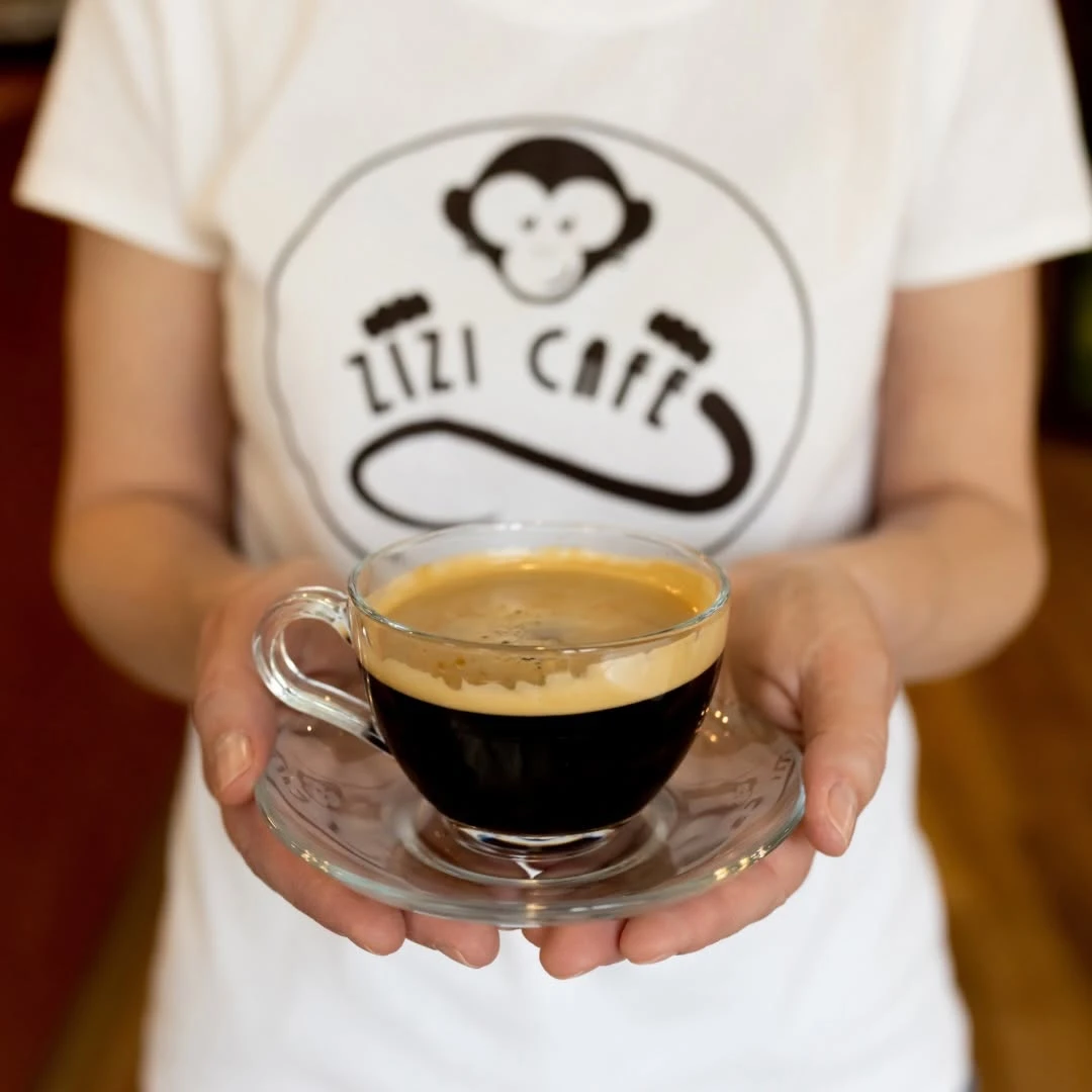 Espresso w szklanej filiżance, w tle koszulka z logo Zizi Cafe