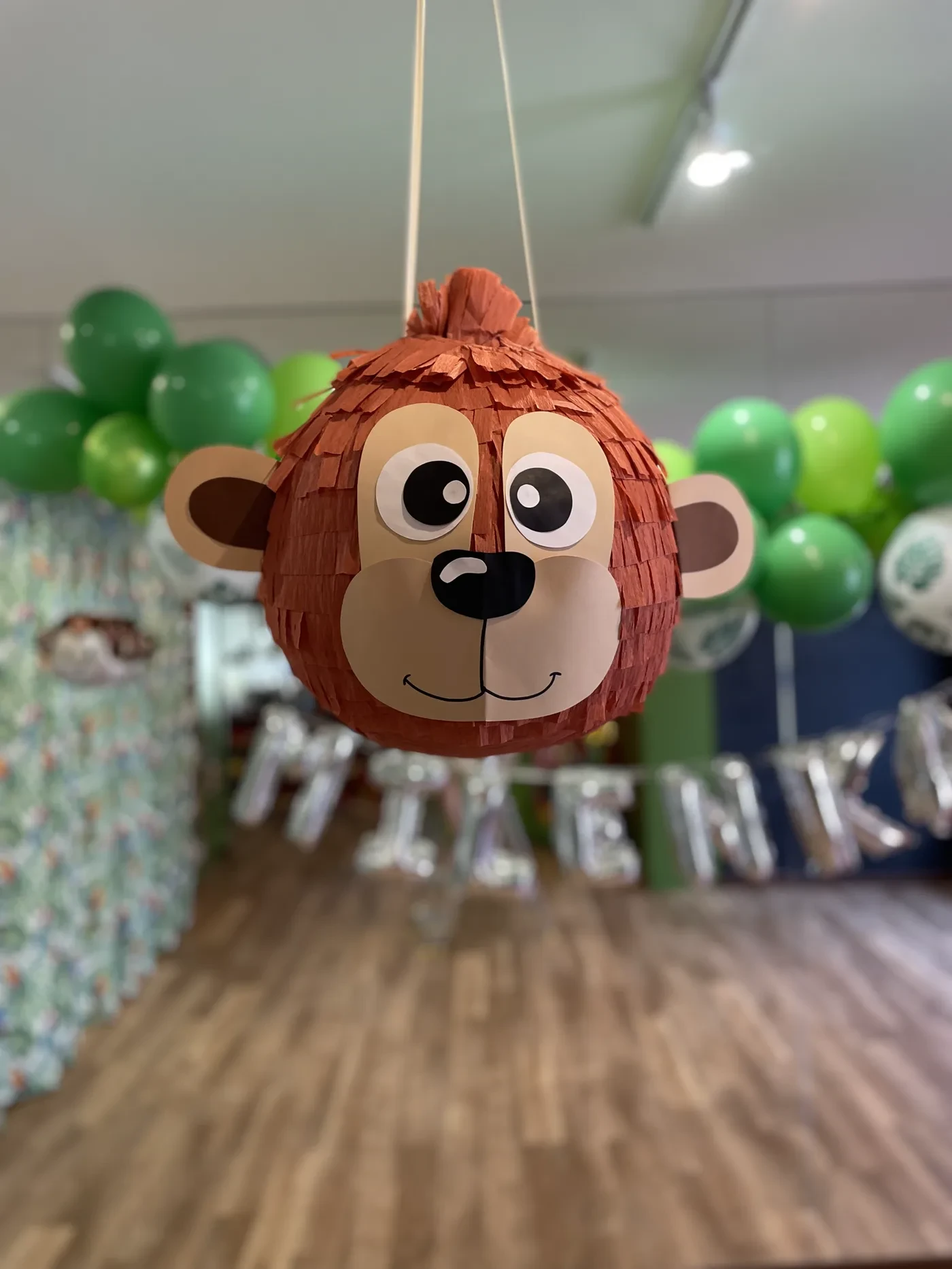 Piniata w kształcie małpki na urodzinach w Zizi Cafe, w tle zielone balony