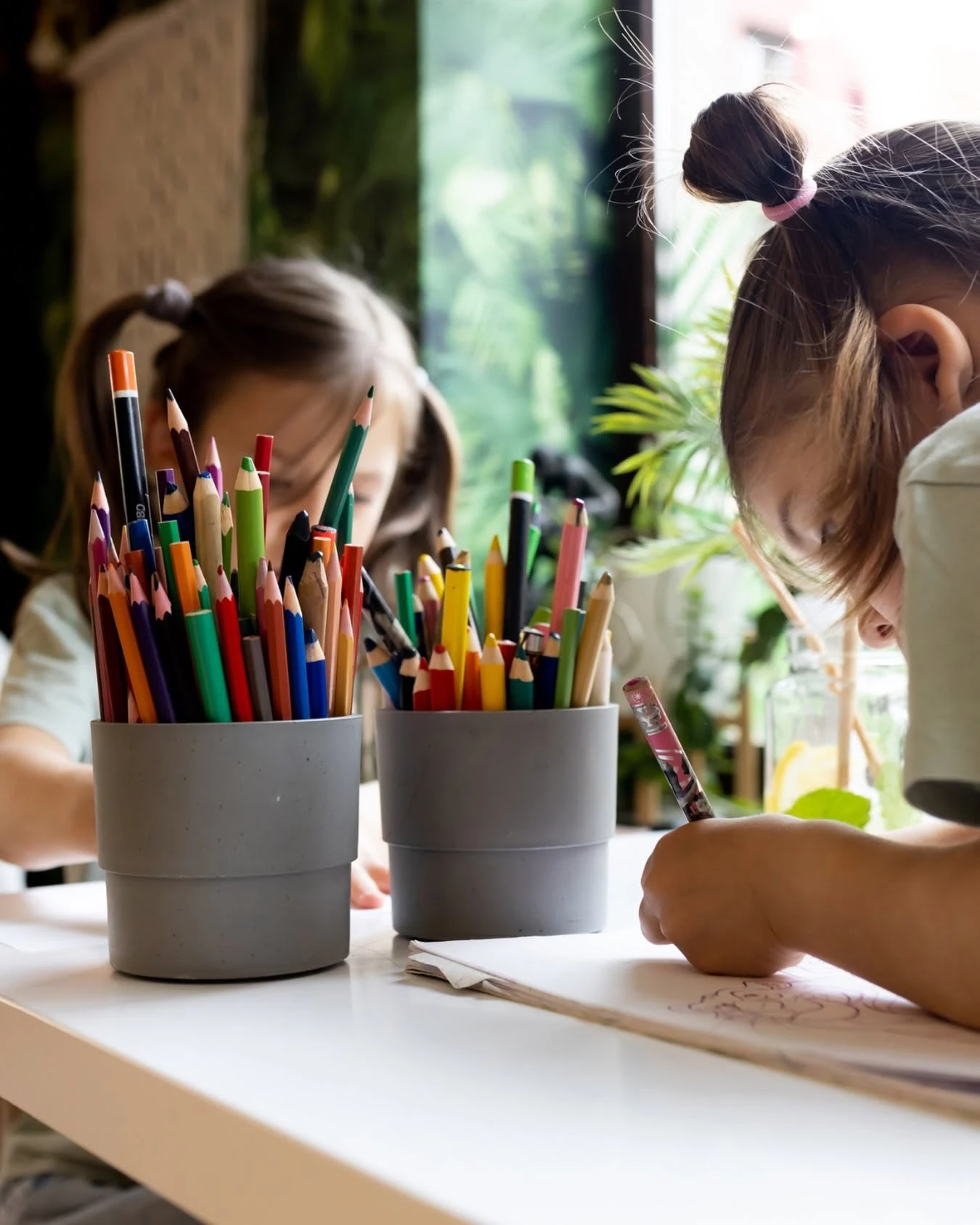 Dziewczynki rysują kredkami przy stole w Zizi Cafe